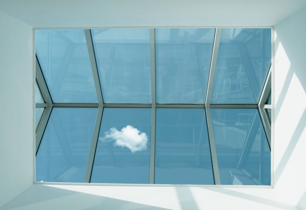 Techo de cristal móvil con estructura de aluminio y paneles de vidrio laminado que permiten ver el cielo, ideal para áticos con sol cenital intenso