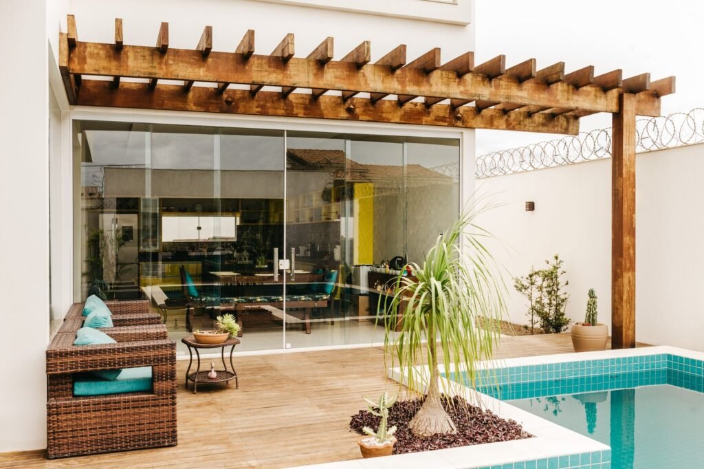 Terraza de villa moderna con pérgola, sofás de exterior, piscina y puertas de cristal correderas