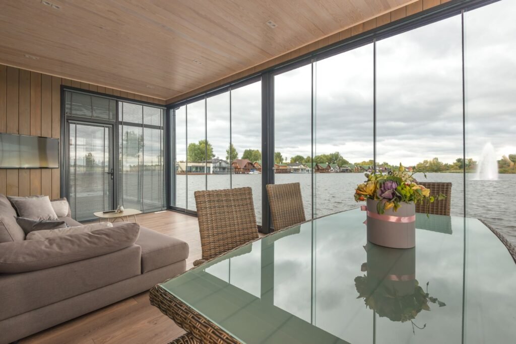 Terraza de chalet de lujo cerrada con paredes de cristal de suelo a techo y perfiles de aluminio, con vistas panorámicas al exterior, ejemplo de cerramiento premium en vivienda residencial.