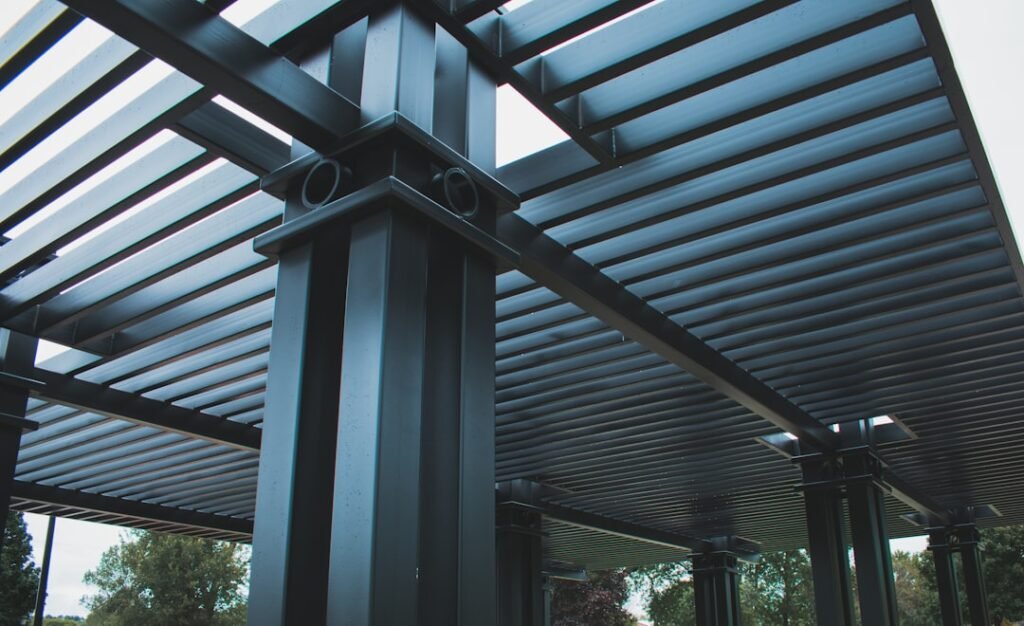 Vista inferior de estructura de pérgola de aluminio con lamas paralelas en color gris oscuro
